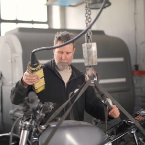 male-mechanic-using-hydraulic-crane-in-garage-3817919